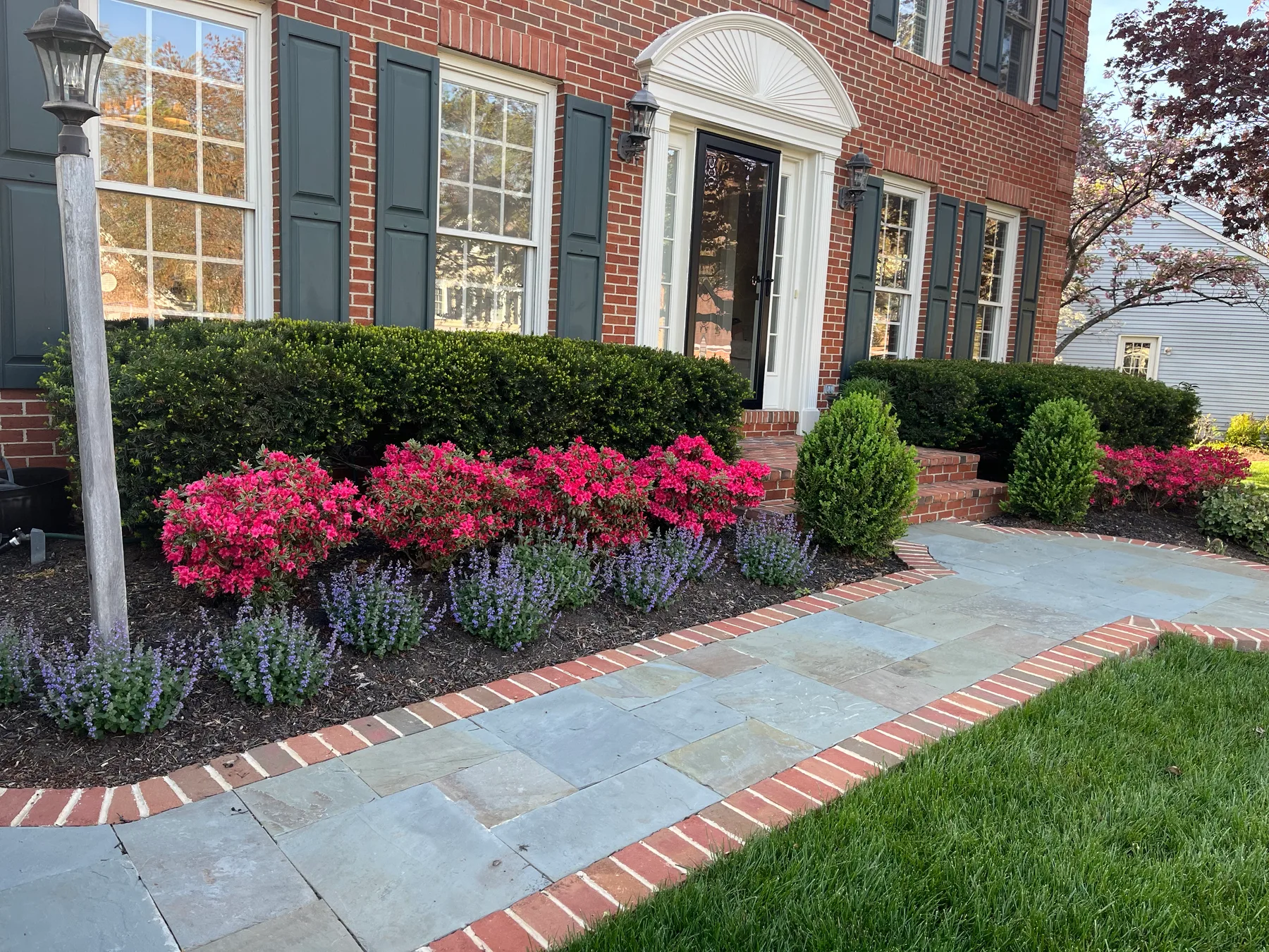 Layered ornamental planting with a custom stone and brick walkway built by Selander Landscape